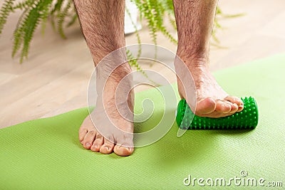 Man doing flatfoot correction gymnastic exercise using massage roller at home Stock Photo