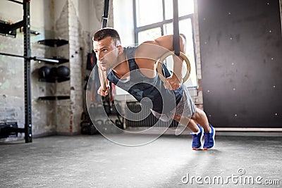 Man doing push-ups on gymnastic rings in gym Stock Photo