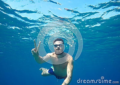 Man doing underwater selfie shot with selfie stick in blue sea Stock Photo