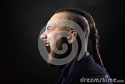 Man with dreadlocks screams in a rage, looks like a viking, Iroquois haircut Stock Photo