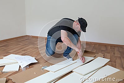 Man dressed casual assembling furniture in new house. Carpenter repair and assembling furniture at home Stock Photo