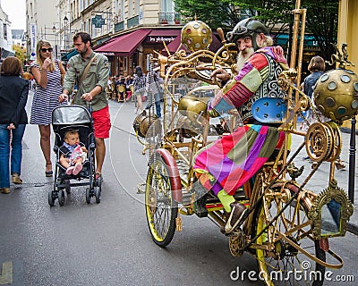 Man dressed in a costume resembling Jules Verne rides his cycle in the streets of Marais Editorial Stock Photo