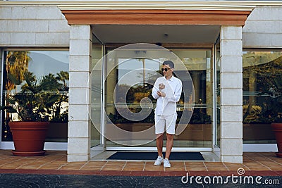 A man dressed in white, leaves the hotel on vacation. Men leaves the hotel, owner. Young businessman on vacation. A man goes on a Stock Photo