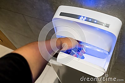 Man dries wet hand in modern vertical hand dryer Stock Photo