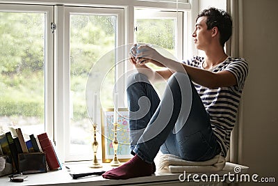 Man, drinking coffee and thinking by window, peace and growth at home, vision and idea for future. Male person, positive Stock Photo