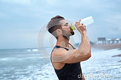 Man Drinking Refreshing Water After Workout At Beach. Drink Stock Photo