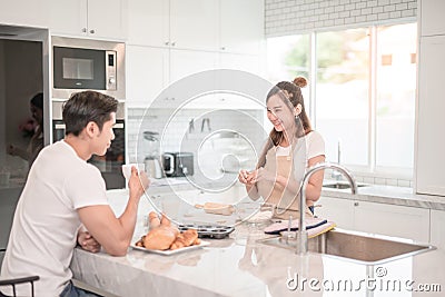 Man drinks coffee while a woman prepares a meal. Stock Photo