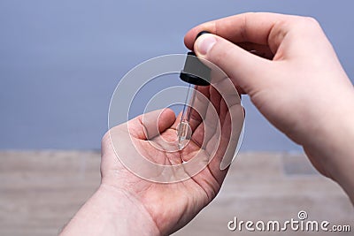 Man dripping oil beard into his palm from a pipette Stock Photo