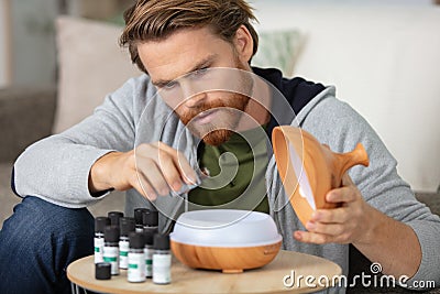man drips essential oil into aromatherapy diffuser Stock Photo