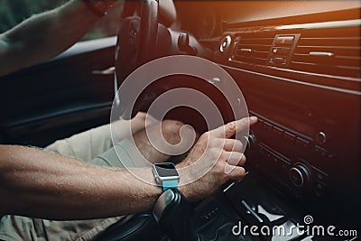 Man driving his car and tuning radio, smart watch on the hand, inside Stock Photo