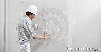 Man drywall worker or plasterer putting plaster on plasterboard wall using a trowel and a spatula, fill the screw holes, wearing Stock Photo