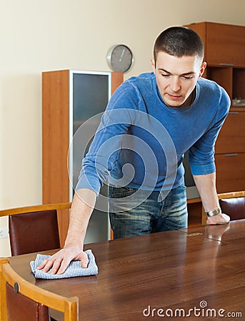 Man dusting table with detergent polish at home Stock Photo