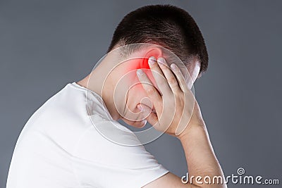 Man with earache, ear pain on gray background Stock Photo