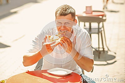 Man eat slice of pizza in street cafe. Happy macho enjoy snack on sunny outdoor, diet. Food and diet concept Stock Photo