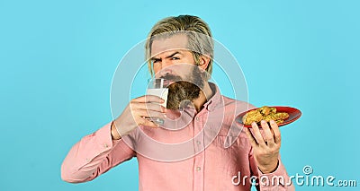 Man eating cookies and drinking milk. cookie and a glass of milk. happy farmer eat cookie dessert. bearded man drink Stock Photo