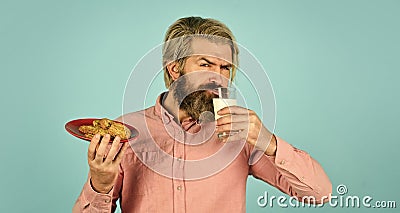 man eating cookies and drinking milk. cookie and a glass of milk. happy farmer eat cookie dessert. bearded man drink Stock Photo
