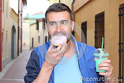 Man eating a Donuts and drinking a shake outdoors Stock Photo