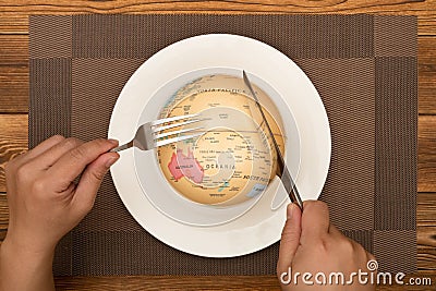 A man eating a globe concept of overusing the resource of nature Stock Photo