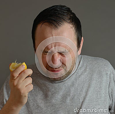 Man eating lemon and making silly faces isolated Stock Photo