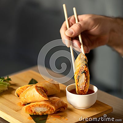 Man Eating Rolls with Sauce Using Chinese Chopsticks. Delicious oriental dish, close up. Eastern Cuisine. Food concept Stock Photo