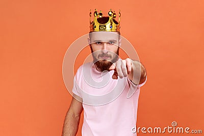 Man egoistically looking at camera posing with crown on head pointing at you with serious expression Stock Photo