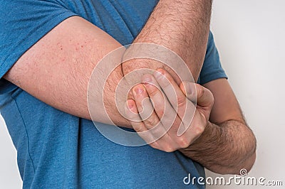 Man with elbow pain is holding his aching arm Stock Photo