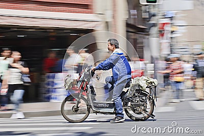 Man on an electric bike passing a shop, Shanghai, China Editorial Stock Photo