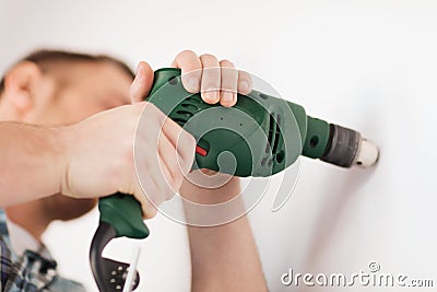 Man with electric drill making hole in wall Stock Photo