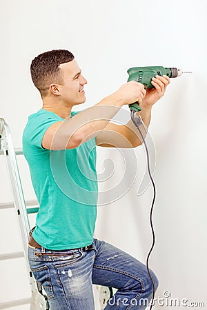 Man with electric drill making hole in wall Stock Photo