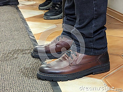 A man in elegant leather shoes leaves wet footprints on the floor indoors. No face Stock Photo