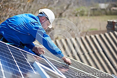 Electrician mounting solar panel on roof of modern house Stock Photo