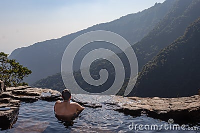 Man enjoying the pristine view at natural swimming pool at mountain cliff from top angles Stock Photo
