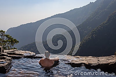 Man enjoying the pristine view at natural swimming pool at mountain cliff from top angles Stock Photo