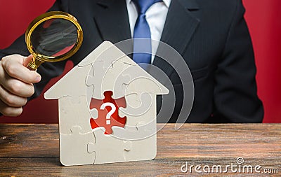 A man examines a house with a missing puzzle inside. Property valuation. Finding problems and structural hidden defects. Checking Stock Photo