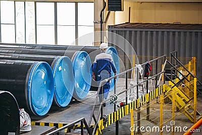 Man examines new coated pipe in warehouse Editorial Stock Photo