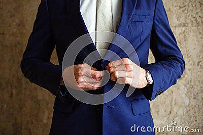 A man fastens buttons blue jacket on his hand his watch Stock Photo