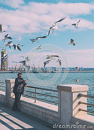 The man feeds birds. Seagulls on the embankment Editorial Stock Photo