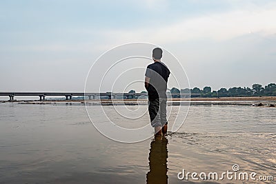 Man feeling the true nature standing in the flowing river with bright sky Stock Photo