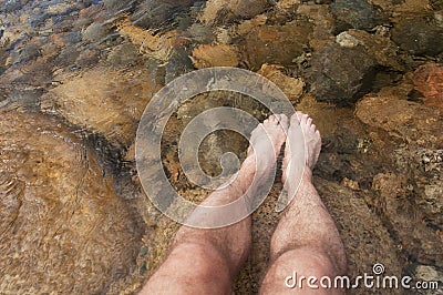 Man with feet in a clear mountain stream Stock Photo