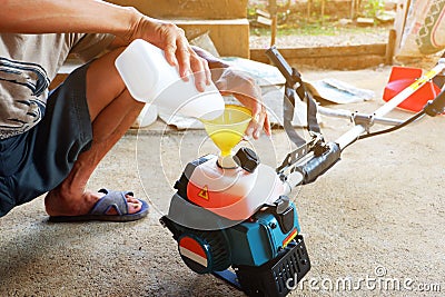 Man is filling fuel Into the fuel tank of Lawn mower Stock Photo