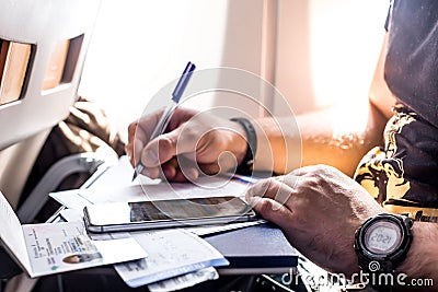 Man filling in immigration form sitting at airplane Stock Photo