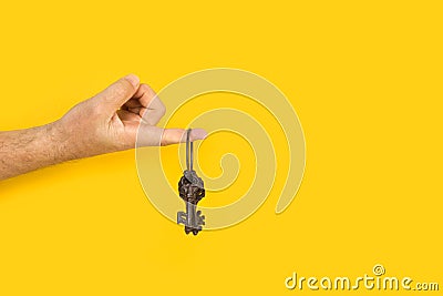 Man finger holding ornate iron keys on a yellow background Stock Photo