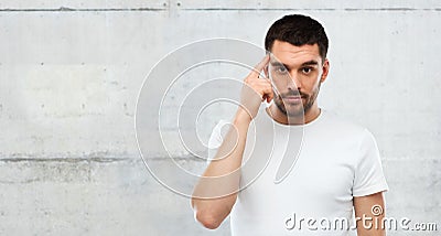 Man with finger at temple over gray wall Stock Photo