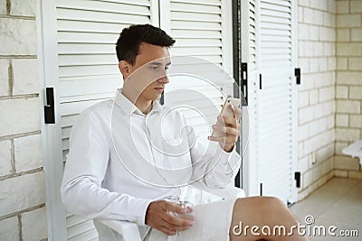 The man finished his wine on the terrace and looks at the phone Stock Photo