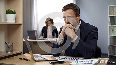 Man finishing typing on laptop, sitting content at desk, exceeded expectations Stock Photo