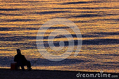 Man Fishing Alone in the Sea at Sunrise or Sunset Editorial Stock Photo