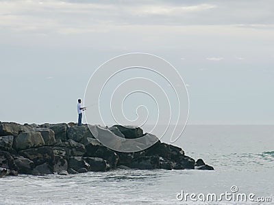 Man fishing on a rocky pier in Newport Beach, California Editorial Stock Photo