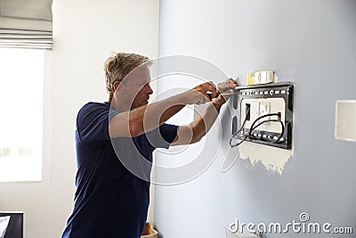 Man Fitting Bracket For Flat Screen TV Onto Wall Stock Photo