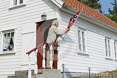 Man fixes national flag at his house in Skudeneshavn, Norway. Editorial Stock Photo