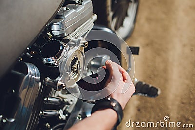 Man fixing bike. Confident young man repairing motorcycle near his garage. Stock Photo